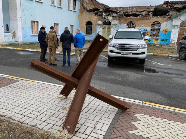 En gruppe på seks menn ser på ruiner i Ukraina.