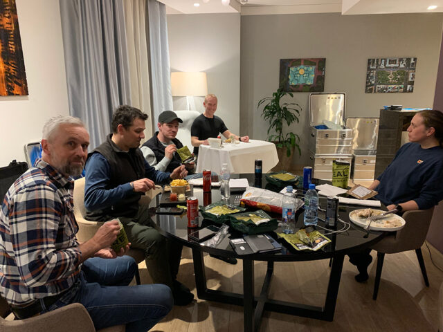 Fem personer sitter rundt et bord og spiser.