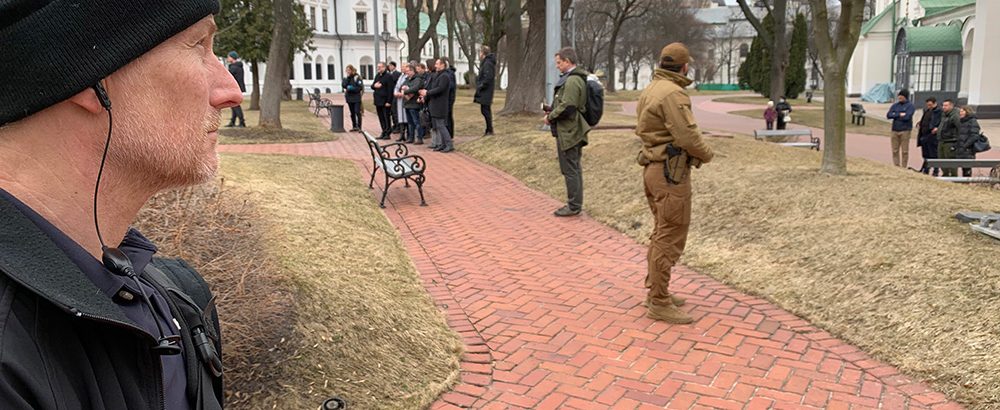 Mann med lue holder vakt i en park.