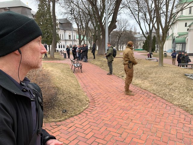 Mann med lue holder vakt i en park.