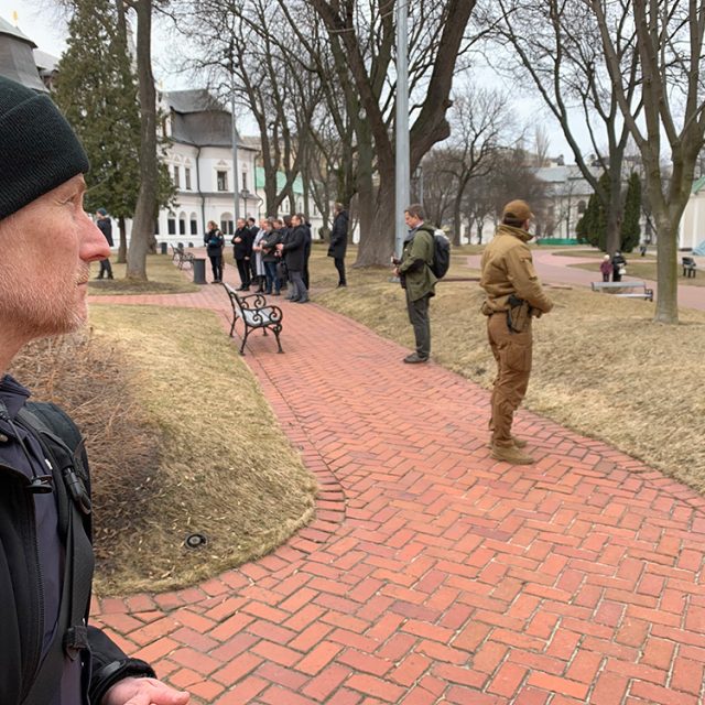 Mann med lue holder vakt i en park.