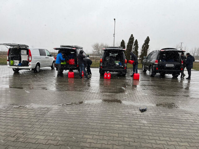 Fire biler med åpen bakluke i regnet.