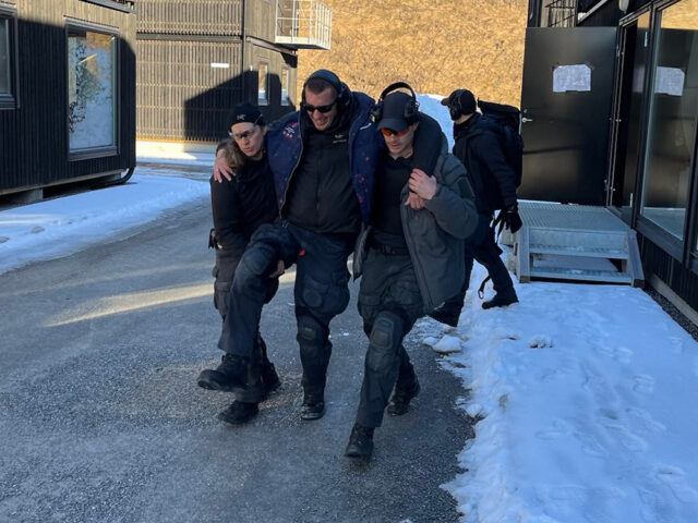 En skadet mann støttes av to kolleger.