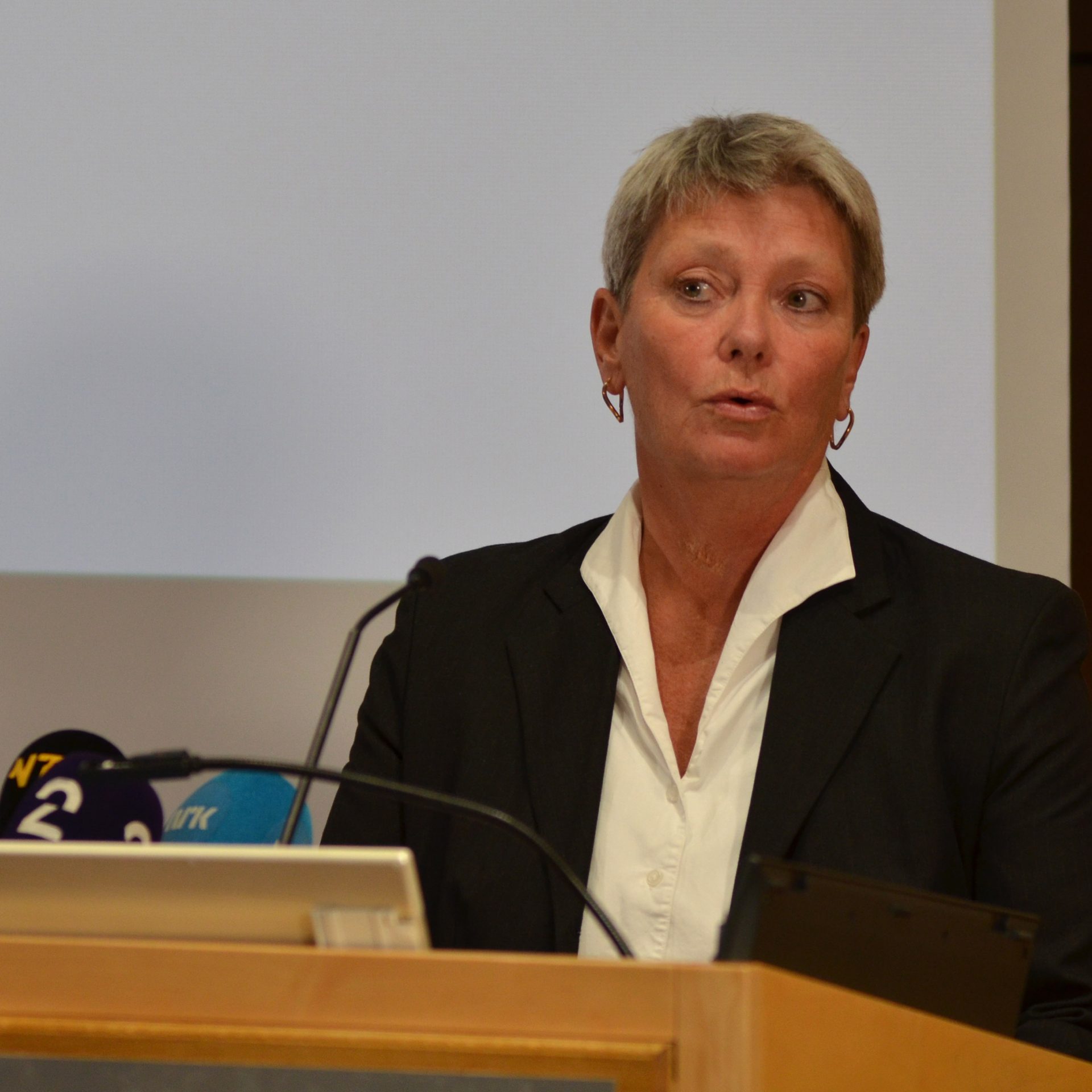 Sjef PST på en scene med mikrofoner foran seg.