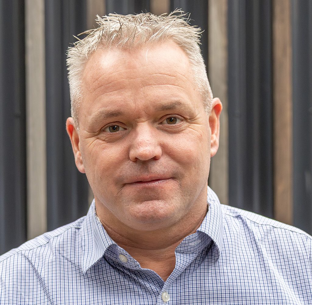 Mann i blåstripete skjorte ser rett i kameraet.