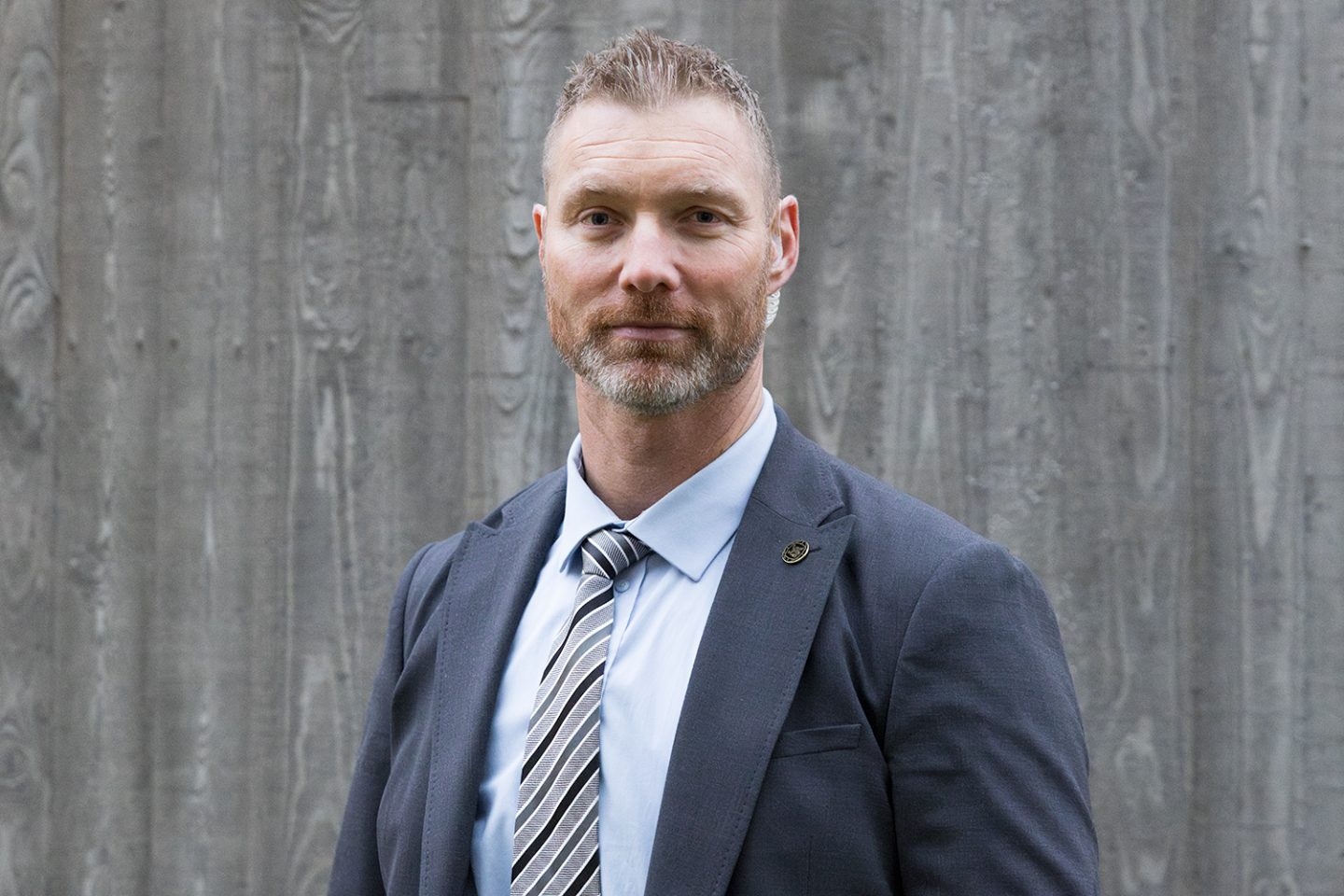 Portrett av en mannlig livvakt i dress. Han ser rett inn i kameraet.