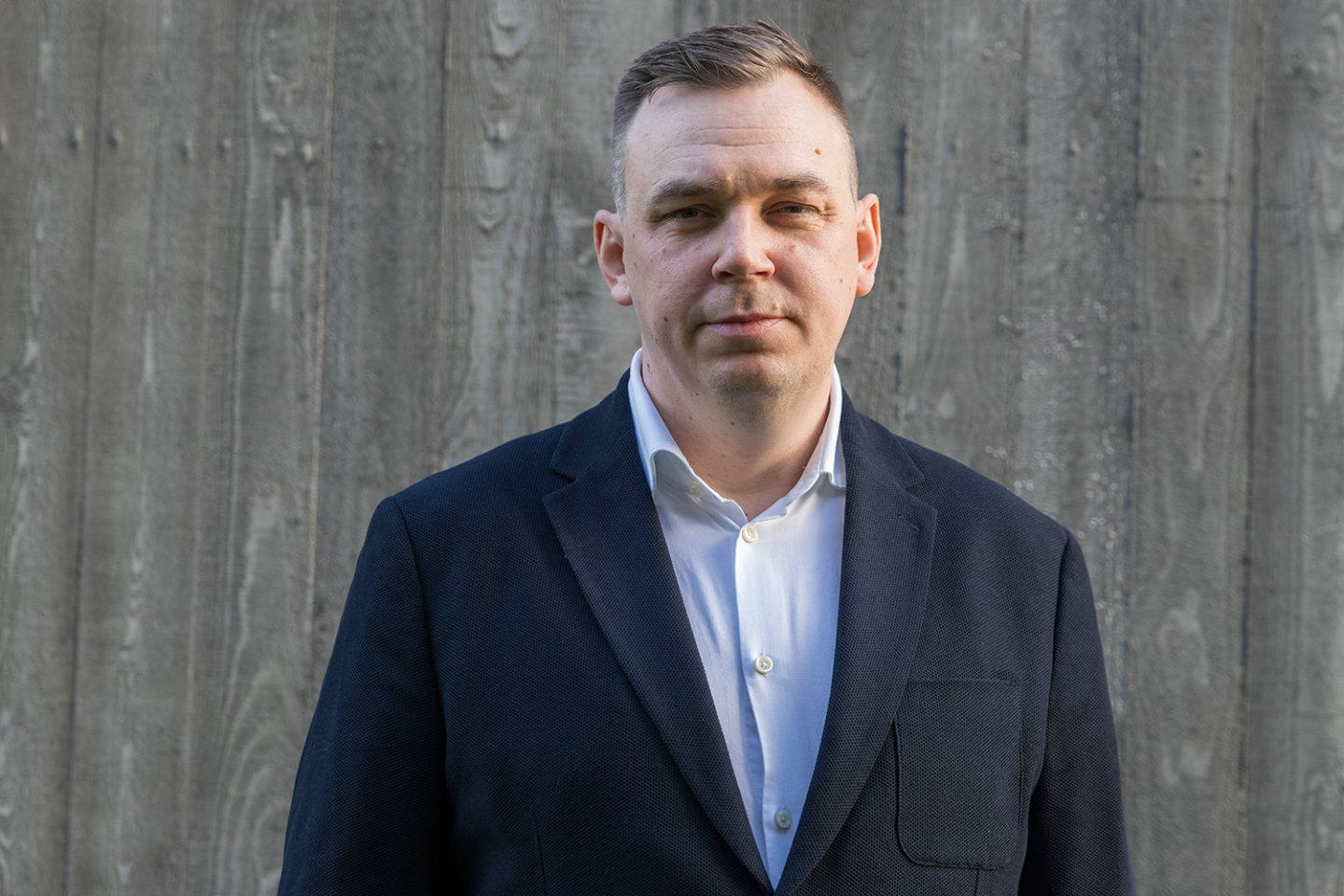 Mann i blazer ser inn mot kameraet.