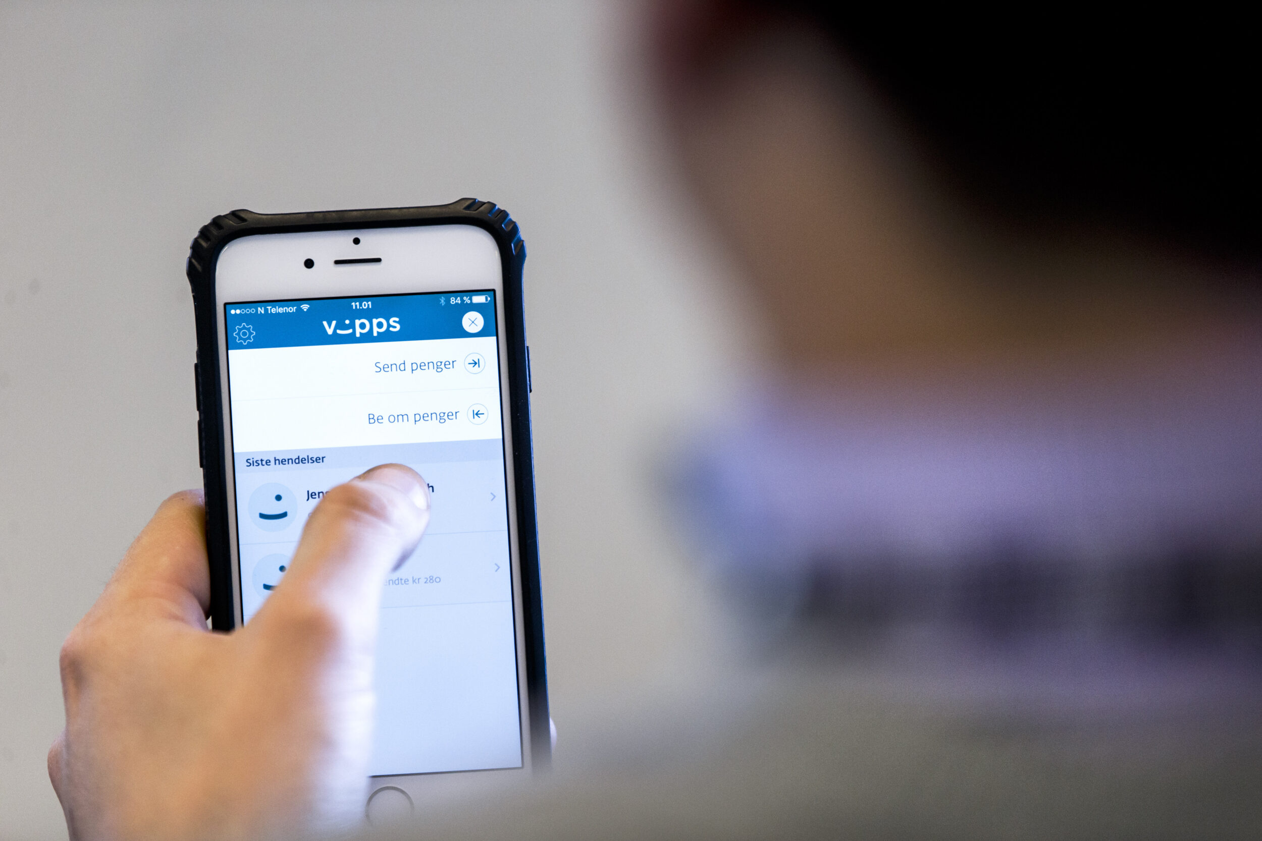 Mann ser på en mobiltelefon. På skjermen er et bilde av Vipps.