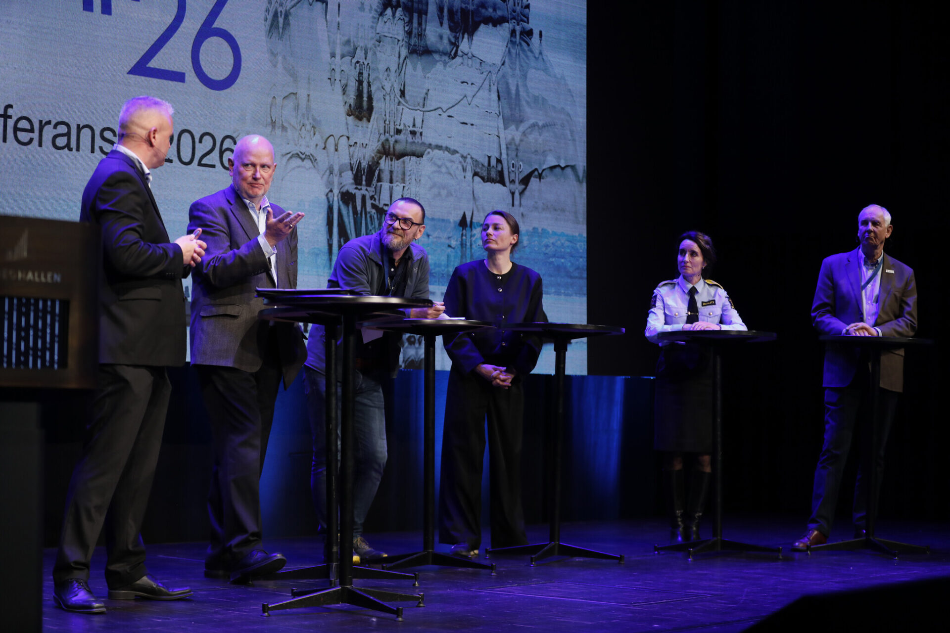 Seks personer på en scene som diskuterer. Foto.