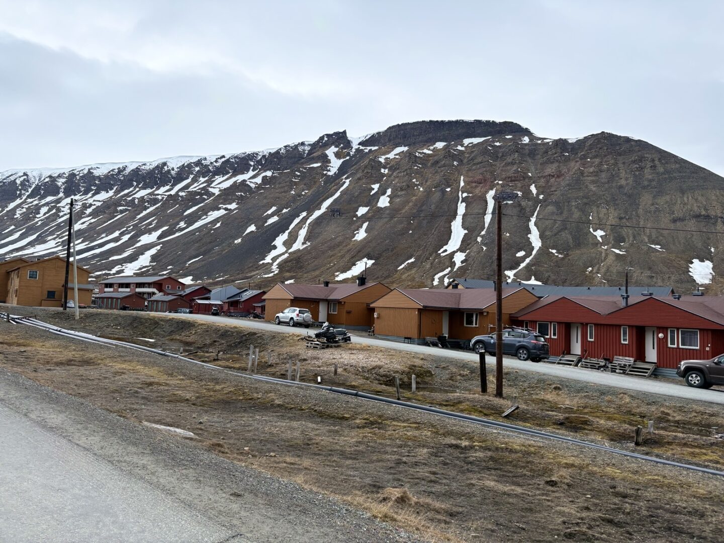 Fargerike hus i Longyearbyen på Svalbard, med store, snødekte fjell i bakgrunnen.
