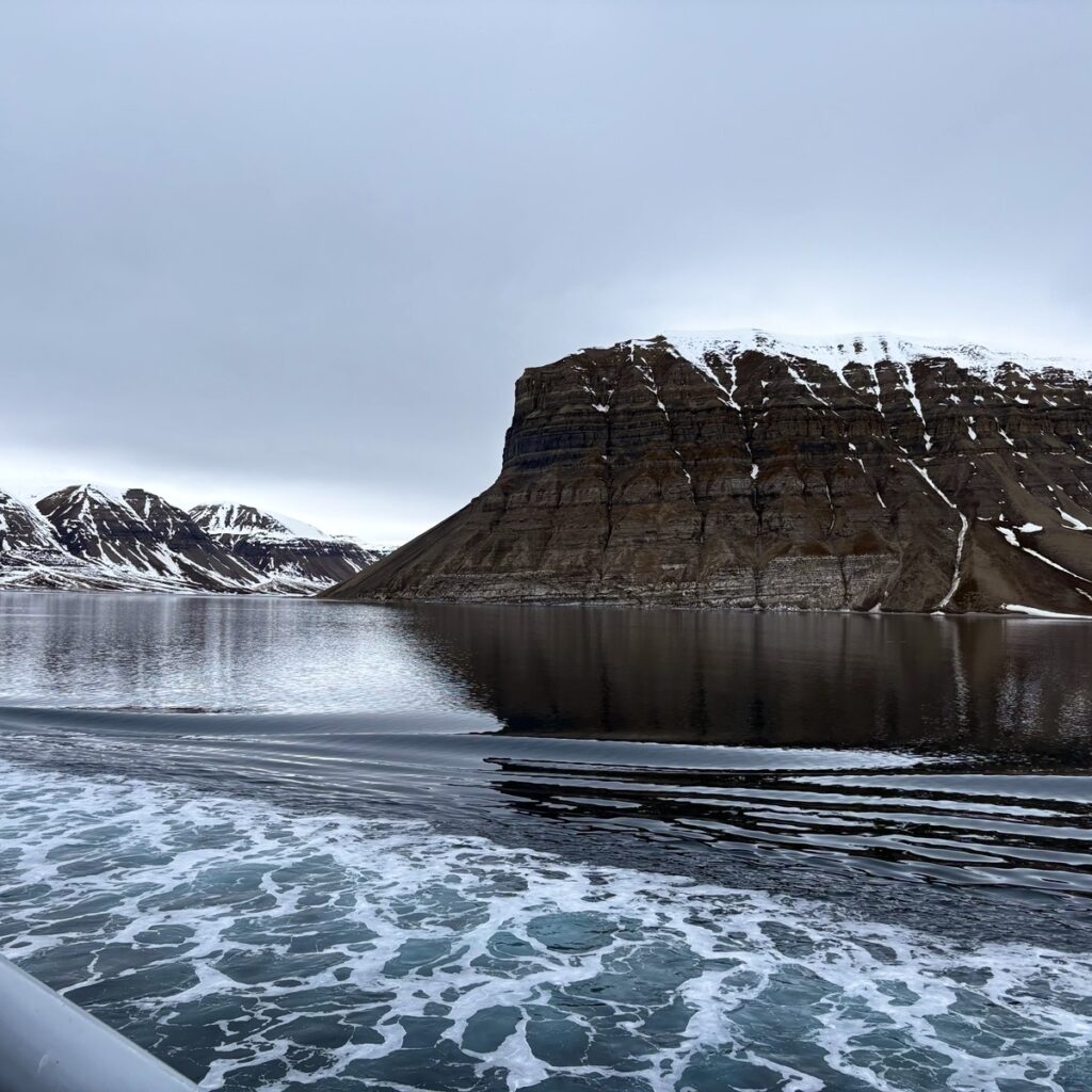 Utsikt fra båt i Svalbard mot snødekte fjell