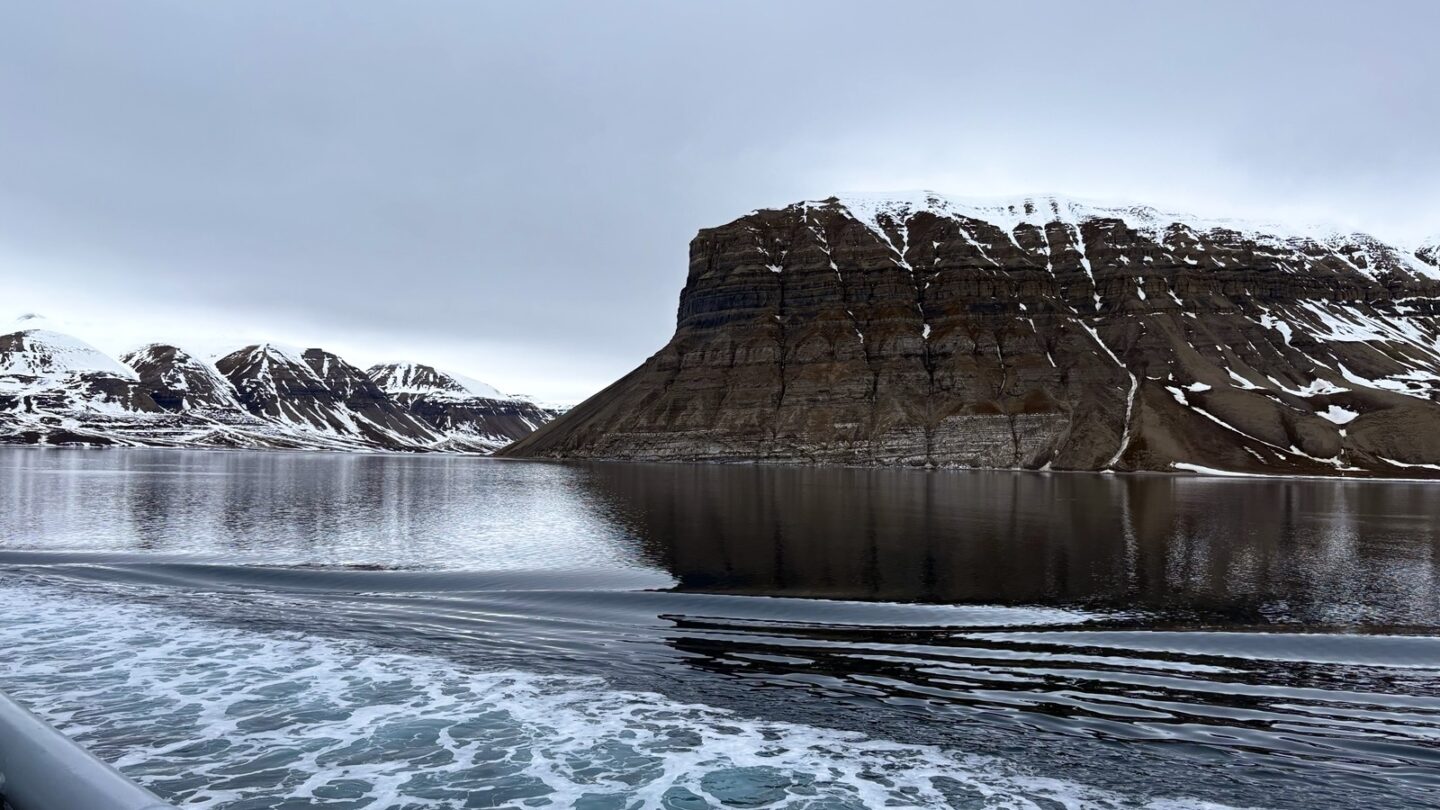 Utsikt fra båt i Svalbard mot snødekte fjell
