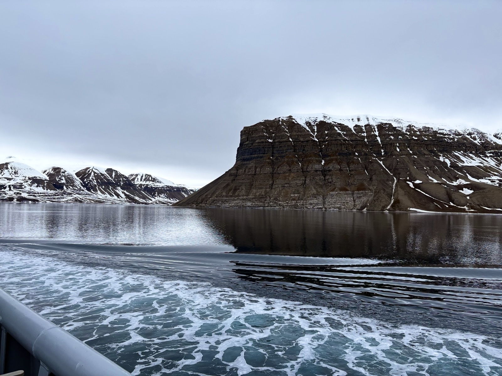 Utsikt fra båt i Svalbard mot snødekte fjell