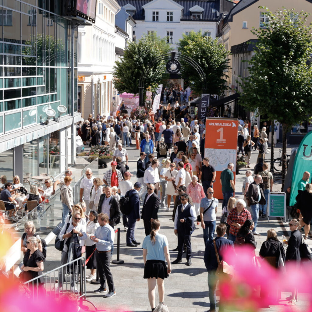 Mange mennesker går i en bygate i Arendal. Foto.